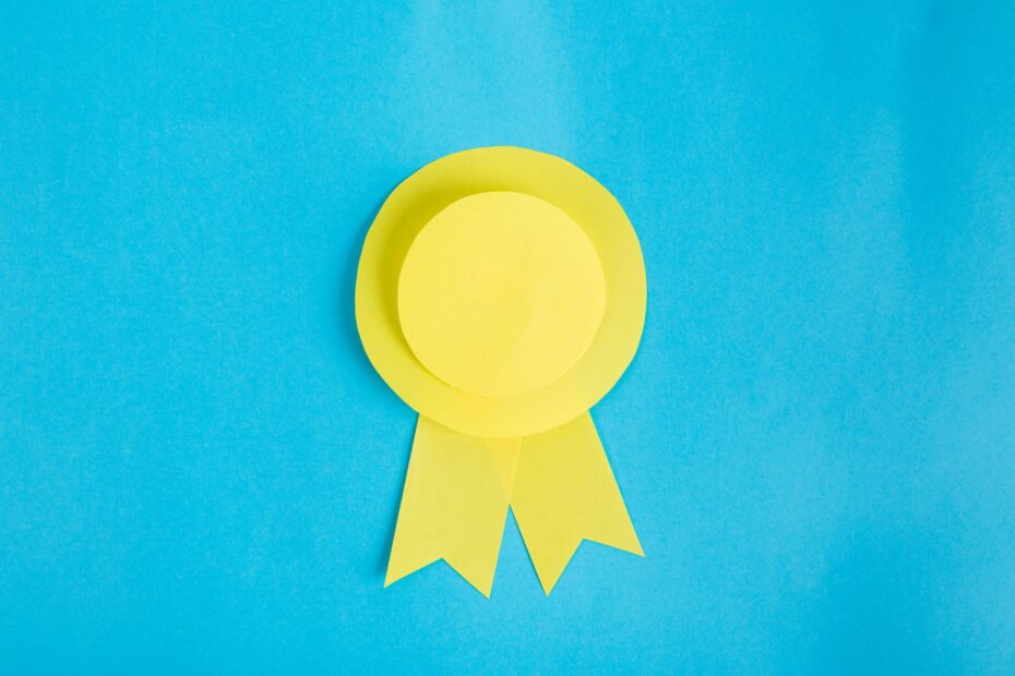 Featured image for our news post Supporters Awards 2022,a blue background with a yellow rosette in the centre.